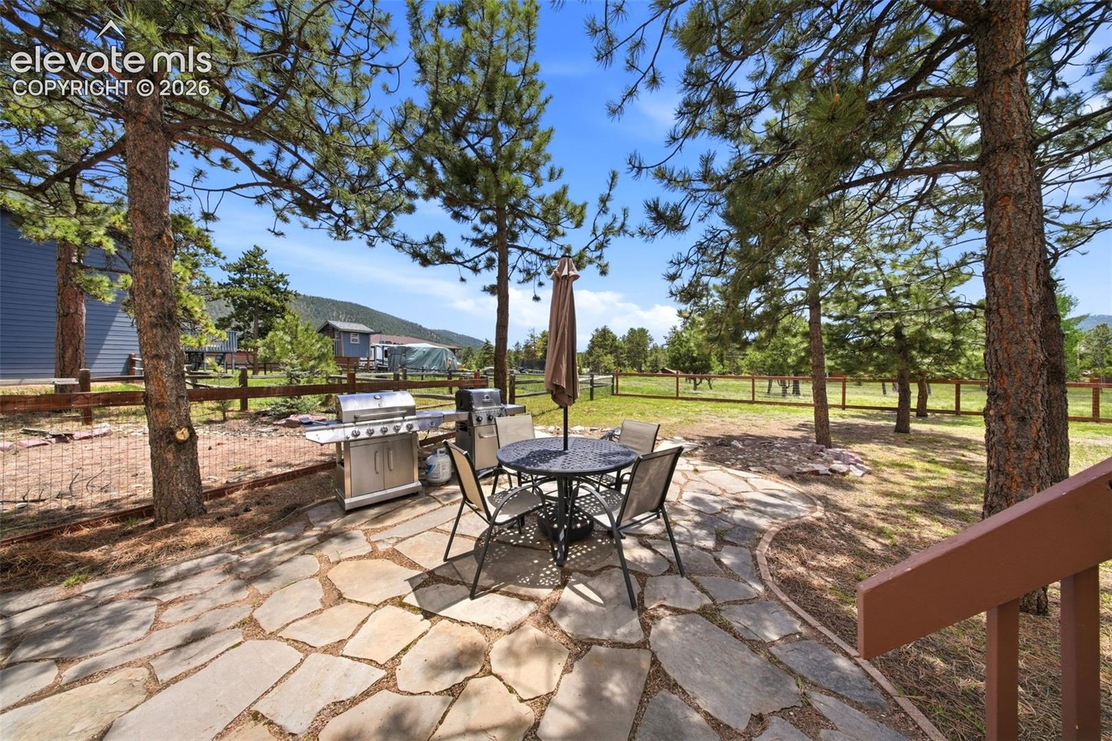 Flagstone patio with an expansive fenced yard and mature pine trees
