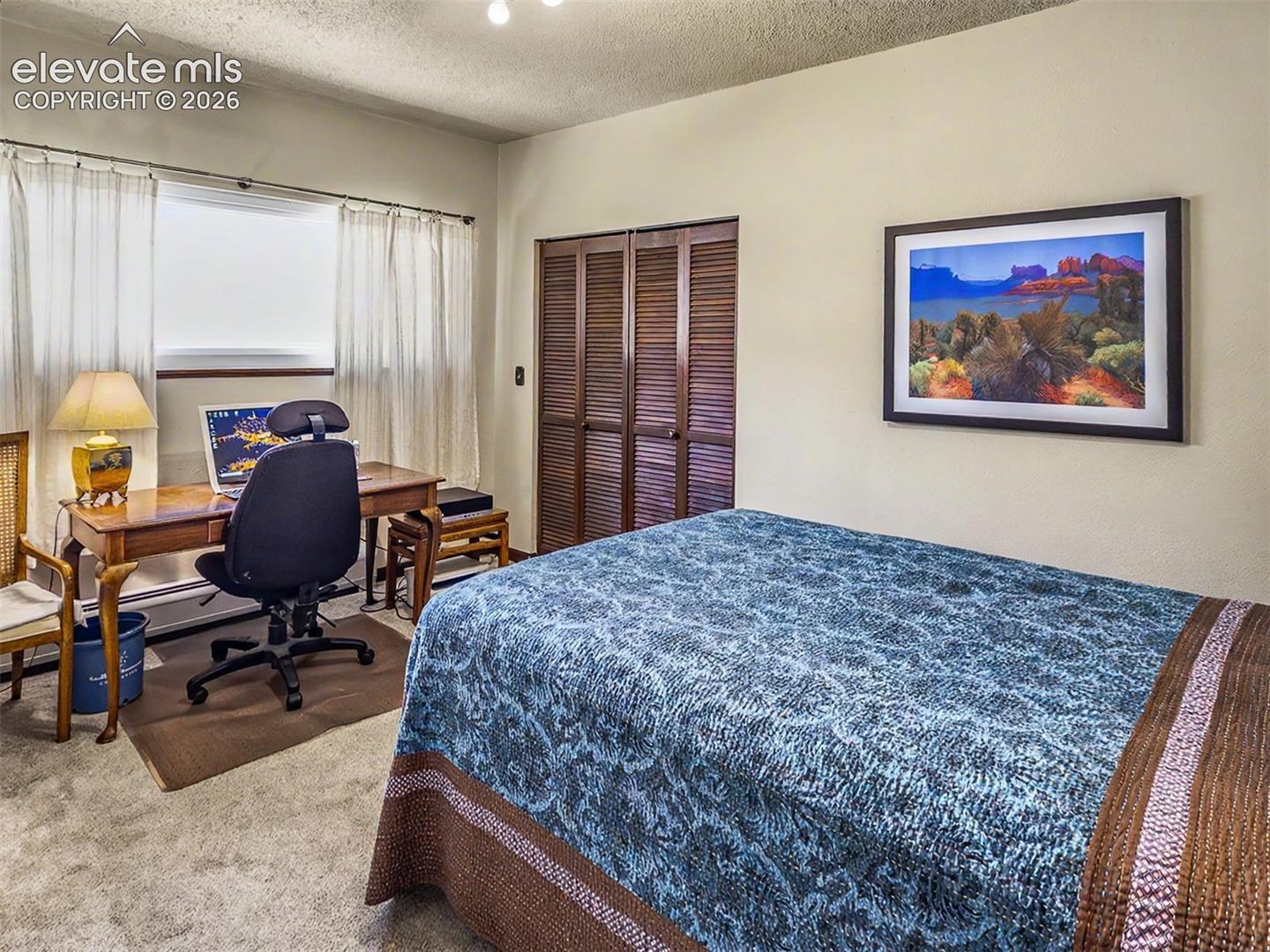 Guest room 2 featuring a window with white curtains, a built-in closet with louvered doors, and light-colored wall paint