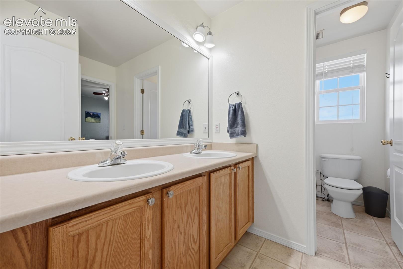 Double vanity with wood-finish cabinetry, chrome fixtures, and a large wall-mounted mirror