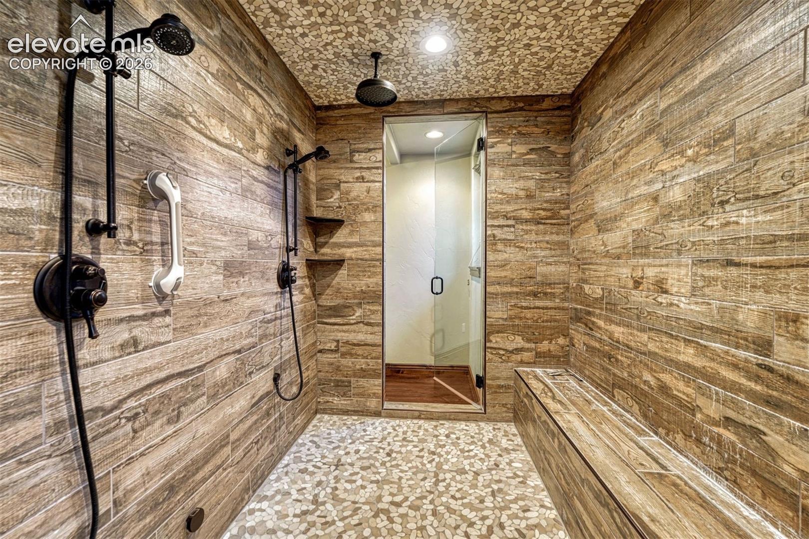 Walk-in shower with wood-look plank wall tiling and pebble-style flooring