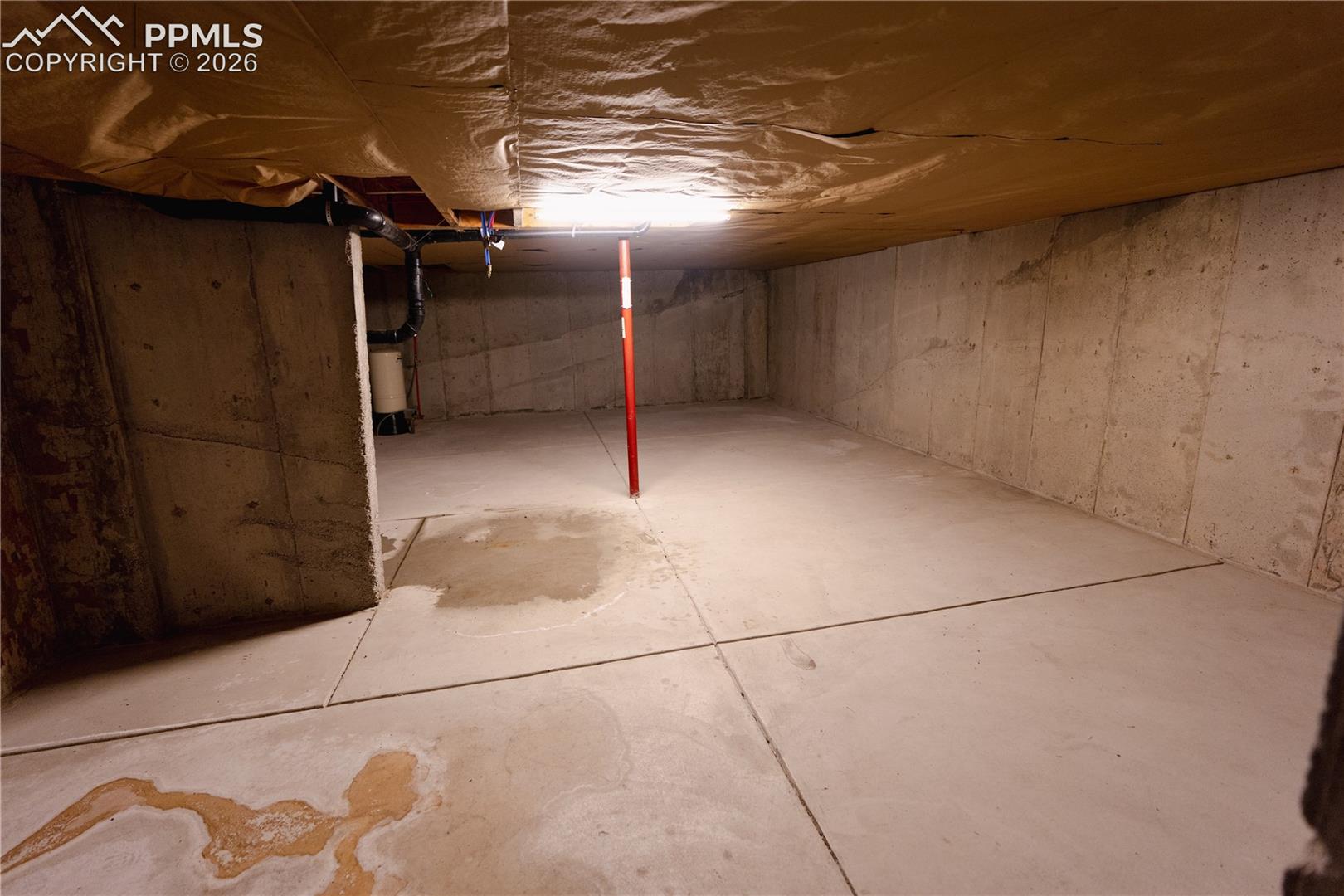 Unfinished basement providing expansive space with concrete walls and floor