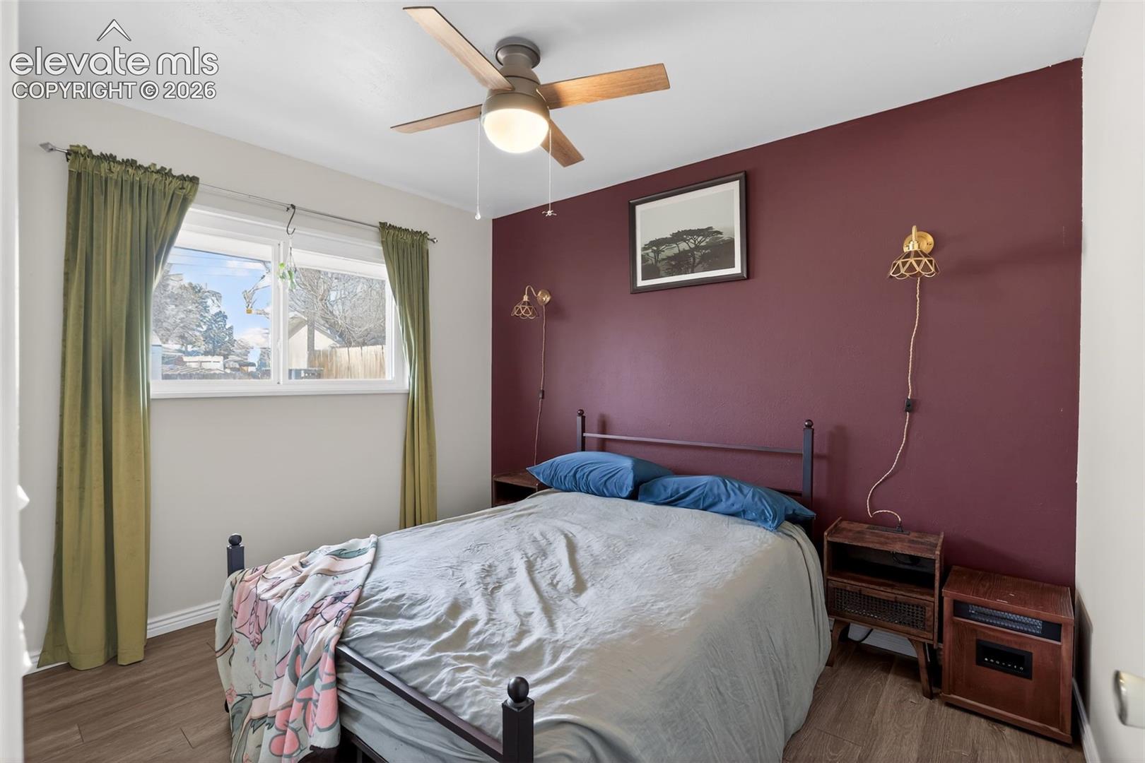 Wood-finish flooring, ceiling fan with integrated lighting, and a window with natural light