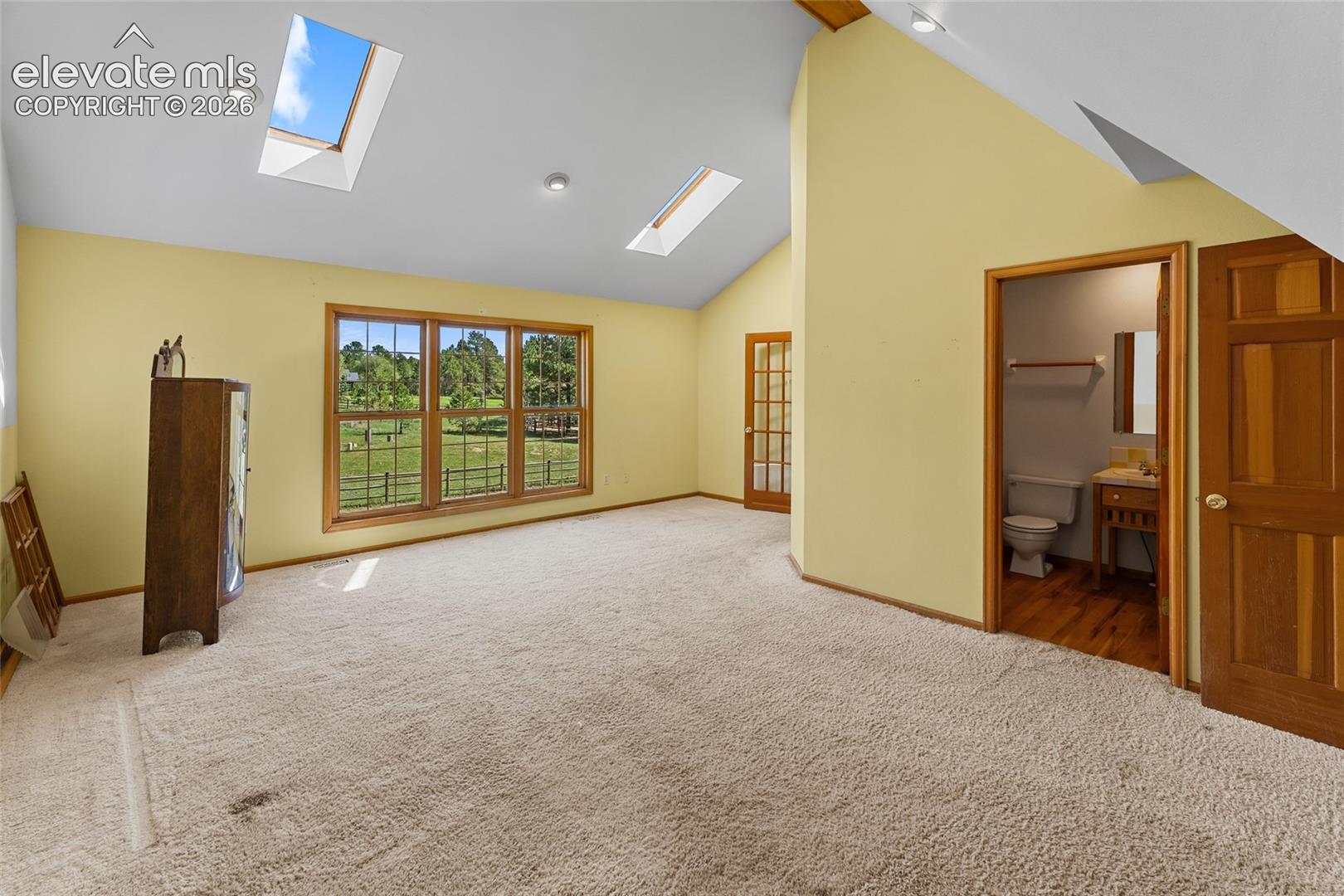 Vaulted ceilings with recessed lighting and skylights, a three-panel window, and a wood-finish door