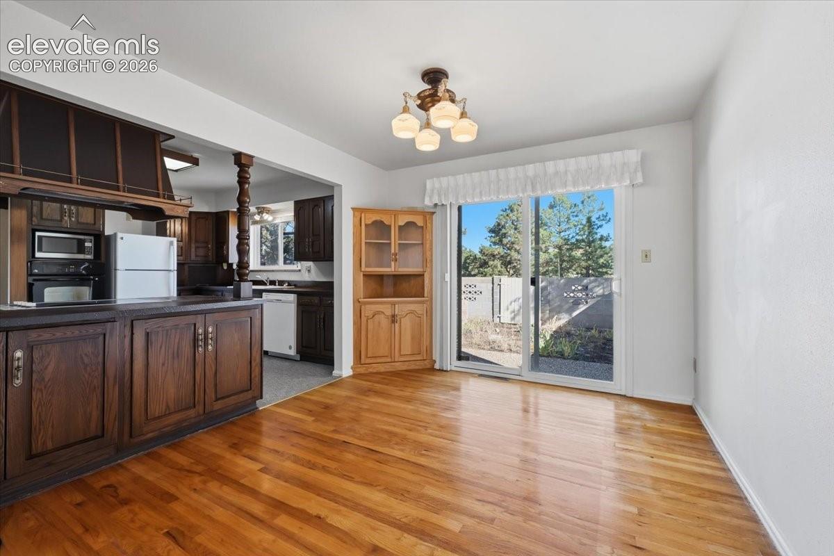 Wood-finish flooring, sliding glass door with exterior access, multi-light ceiling fixture, and built-in cabinetry