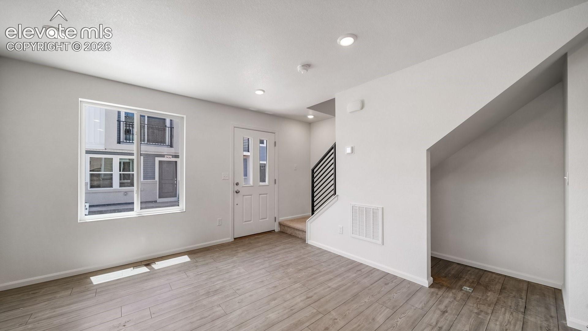 Recessed lighting, wood-finish flooring, white paneled entry door, white trim throughout, and a modern stair railing
*photos of a model home*