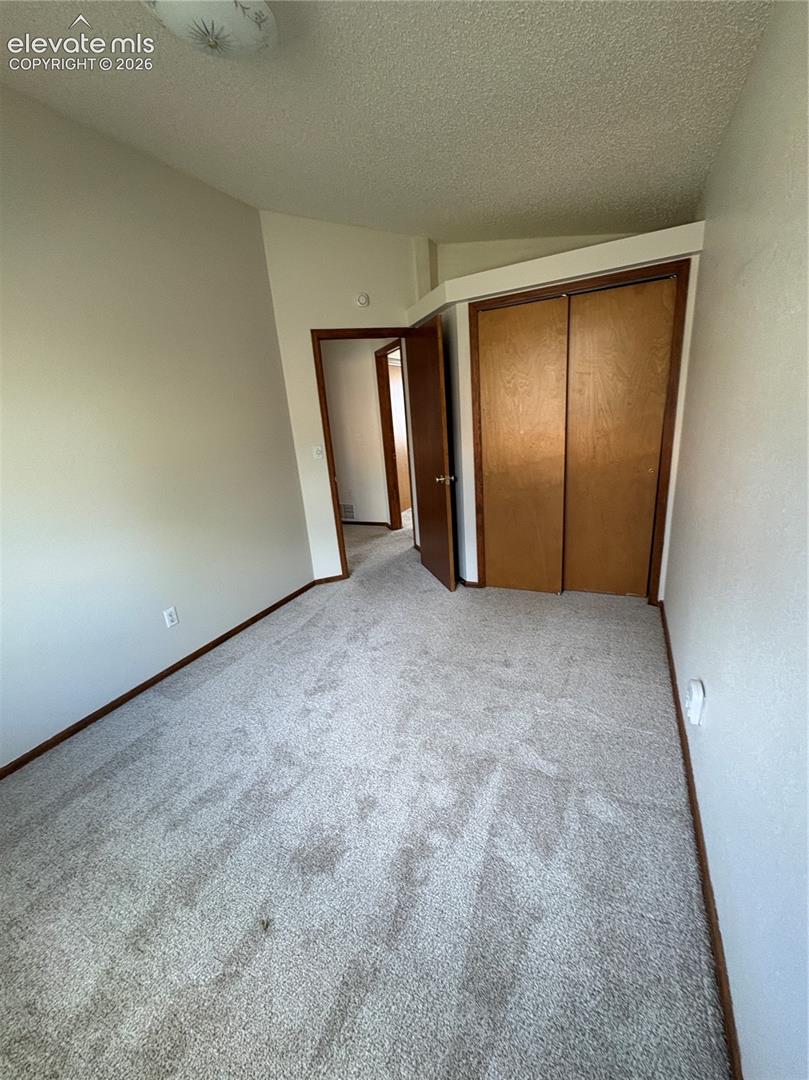 Interior room featuring neutral wall paint, wall-to-wall carpeting, wood-finish sliding closet doors, and a ceiling-mounted light fixture