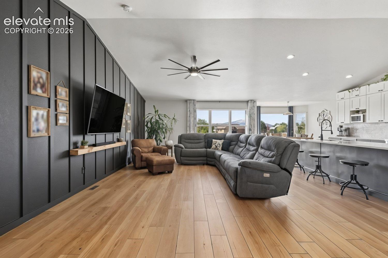 Open-concept living space with luxury vinyl flooring, vaulted ceilings, floating wood shelf