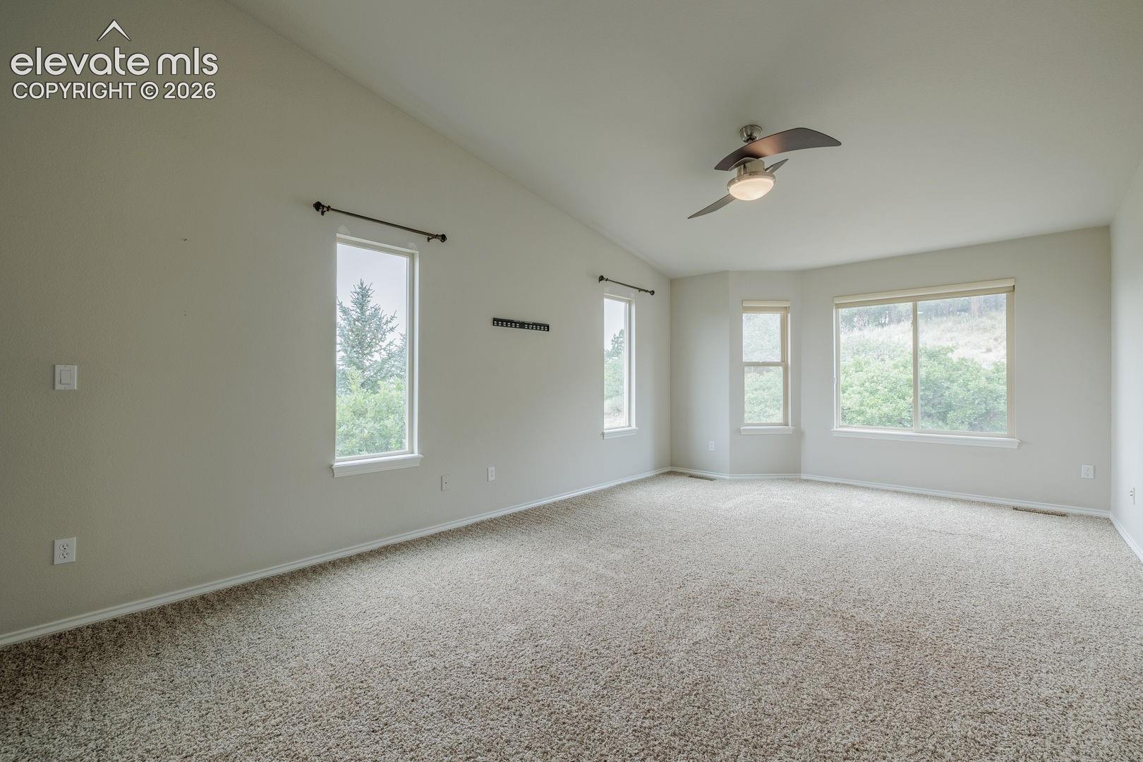  main bedroom featuring vaulted ceilings, a contemporary ceiling fan with integrated lighting, and neutral carpeting