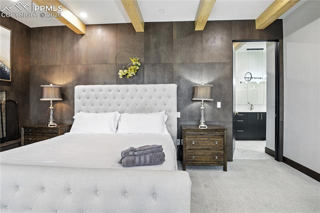 Carpeted bedroom with beamed ceiling and wooden walls