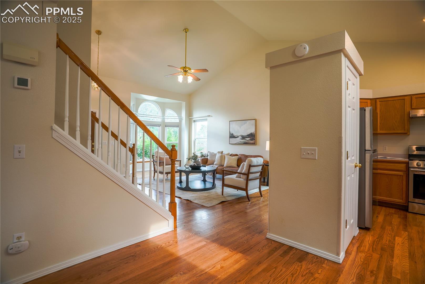 Entrance foyer with stairway, wood finished floors, ceiling fan, and high vaulted ceiling