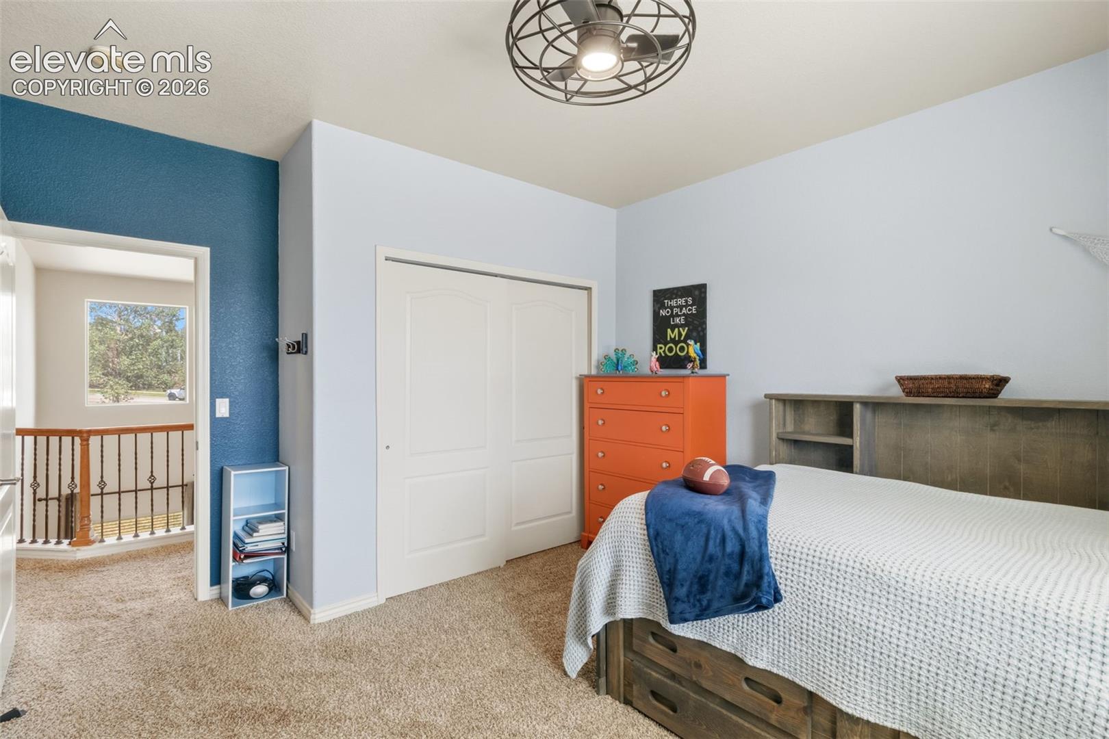 Carpeted bedroom featuring a built-in closet with bi-fold doors, a ceiling fan with integrated lighting, and a window providing natural light
