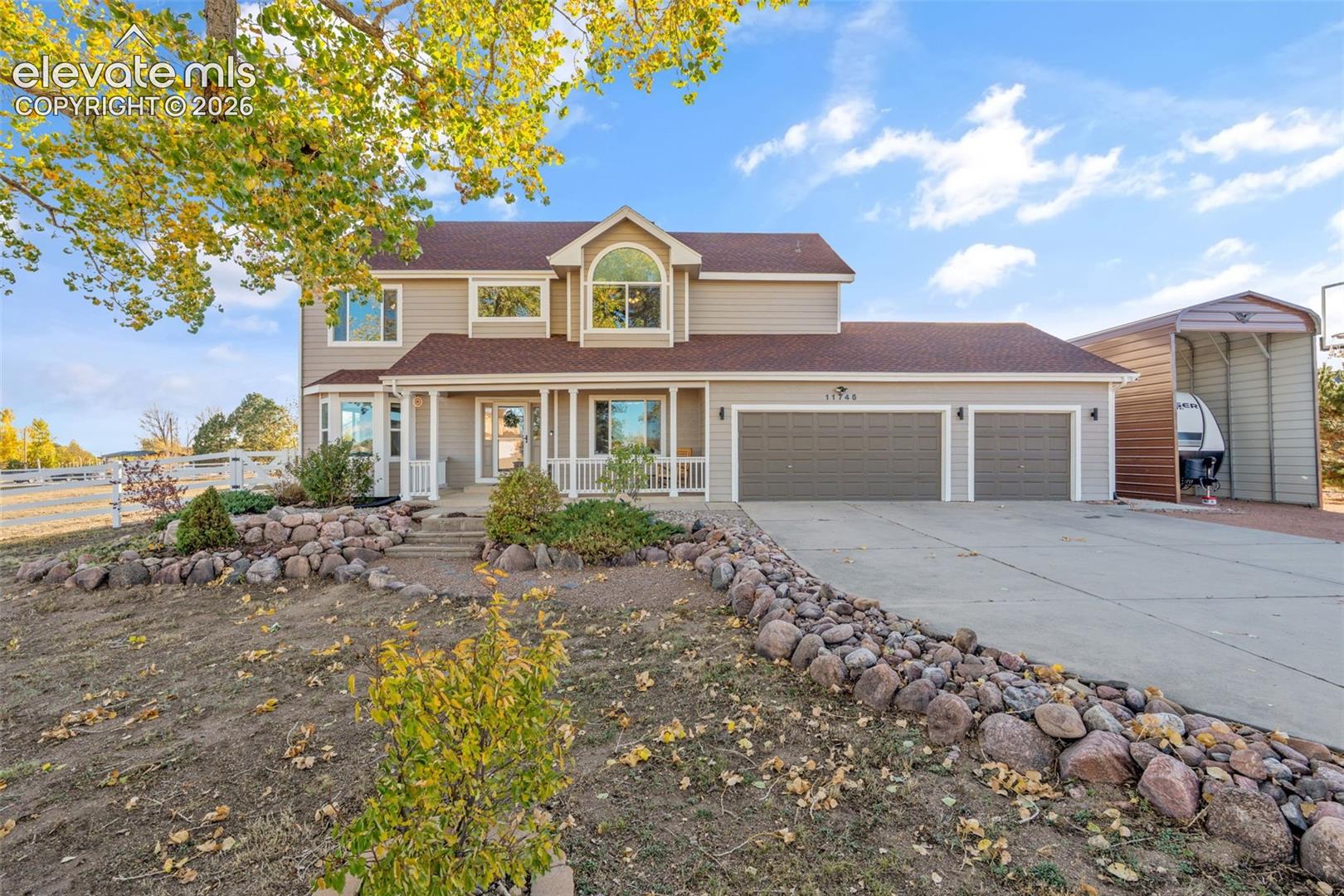 Two-story residence featuring horizontal siding, a covered front porch, an arched window, a three-car garage, and a detached metal carport