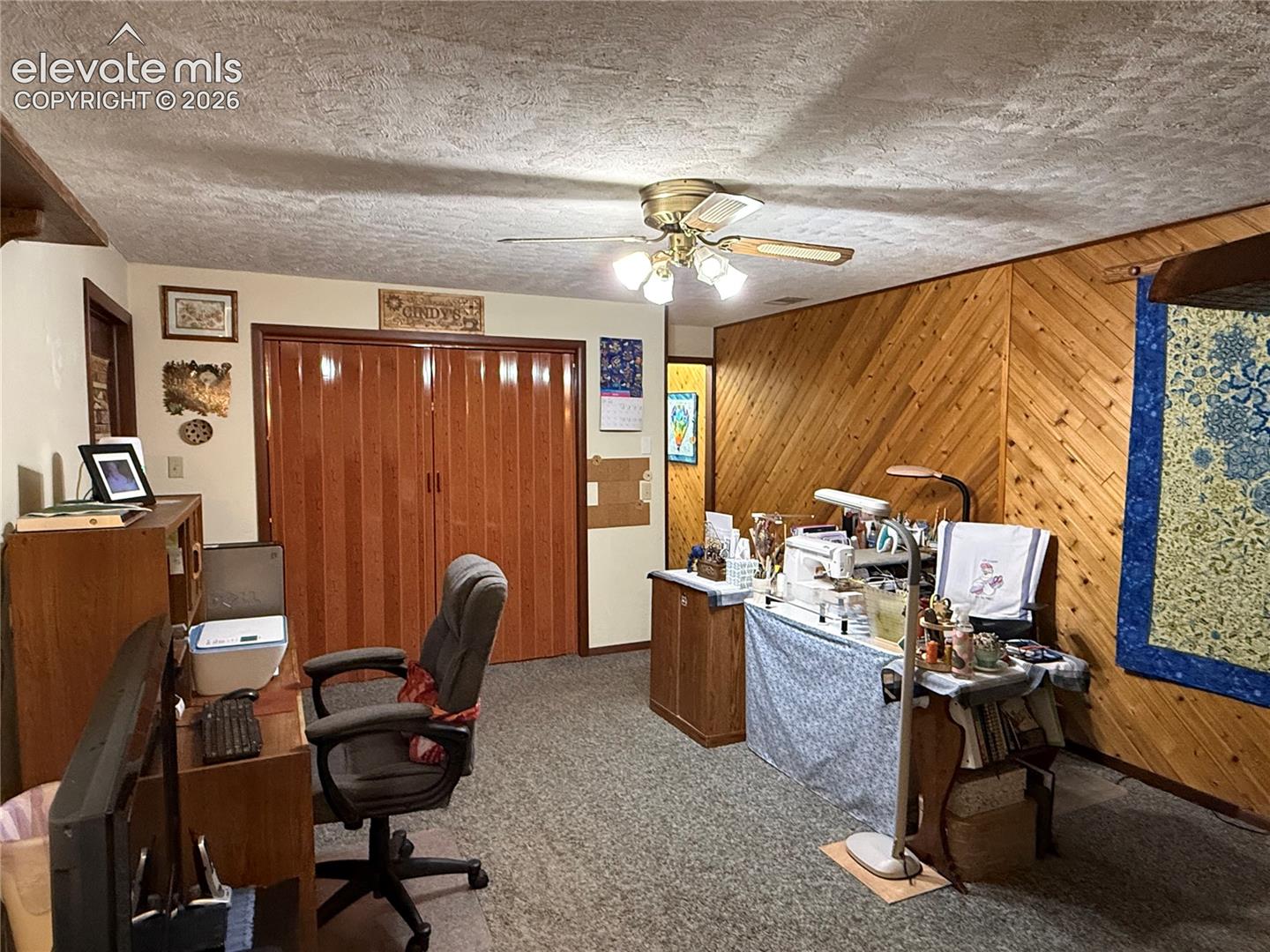 Room featuring light-colored walls, wood-paneled accent wall, and textured ceiling