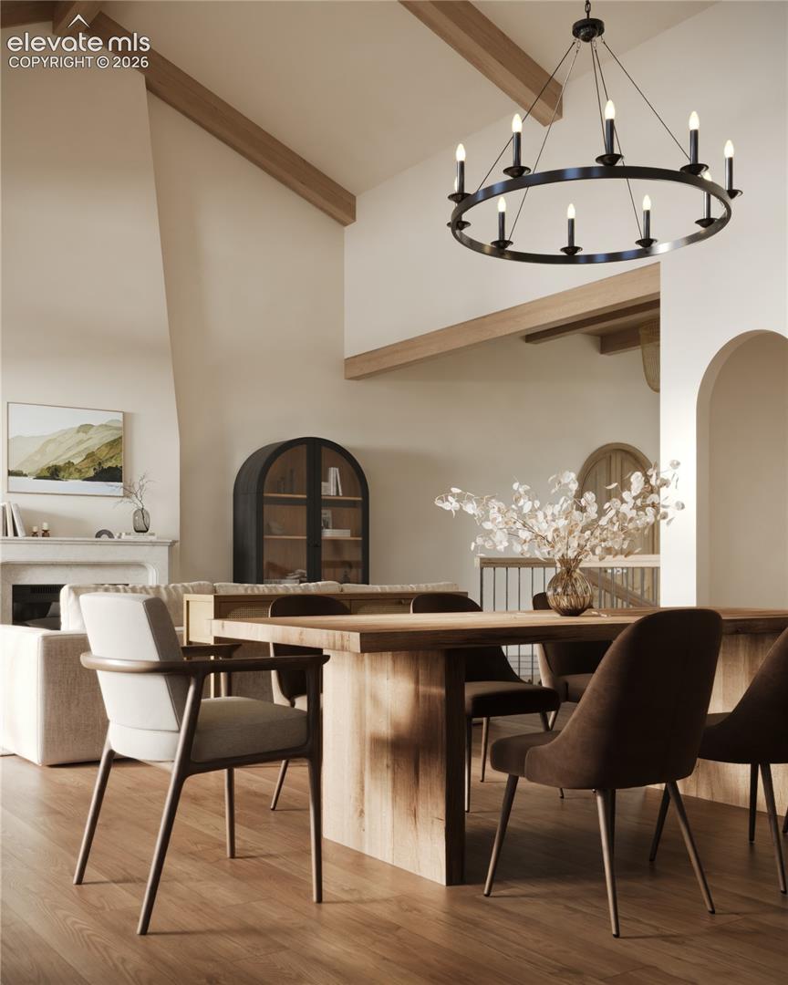 Vaulted ceiling with exposed wood beams, wood-finish flooring, fireplace, and a built-in arched display cabinet