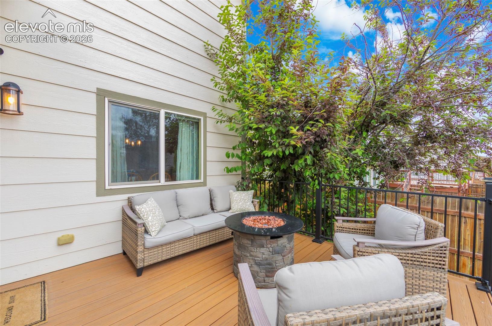 Private exterior deck featuring composite decking, white siding, and a black metal railing