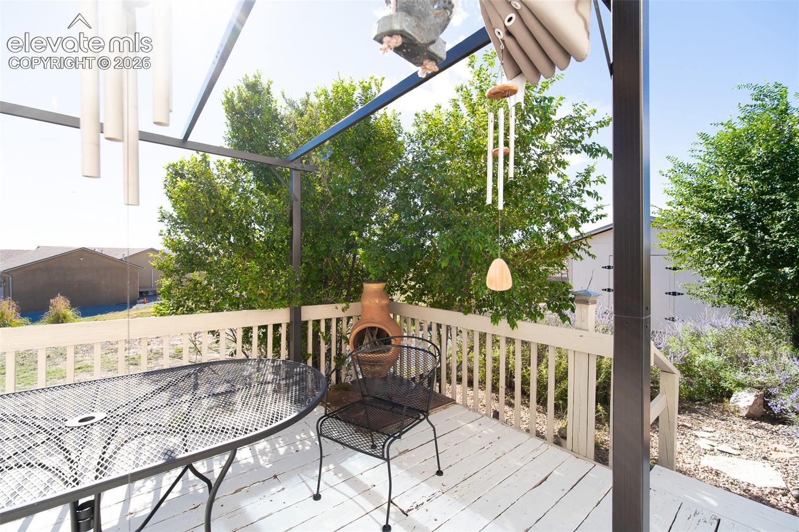 Outdoor deck featuring painted wood-finish decking, a metal frame pergola, and a wrap-around railing