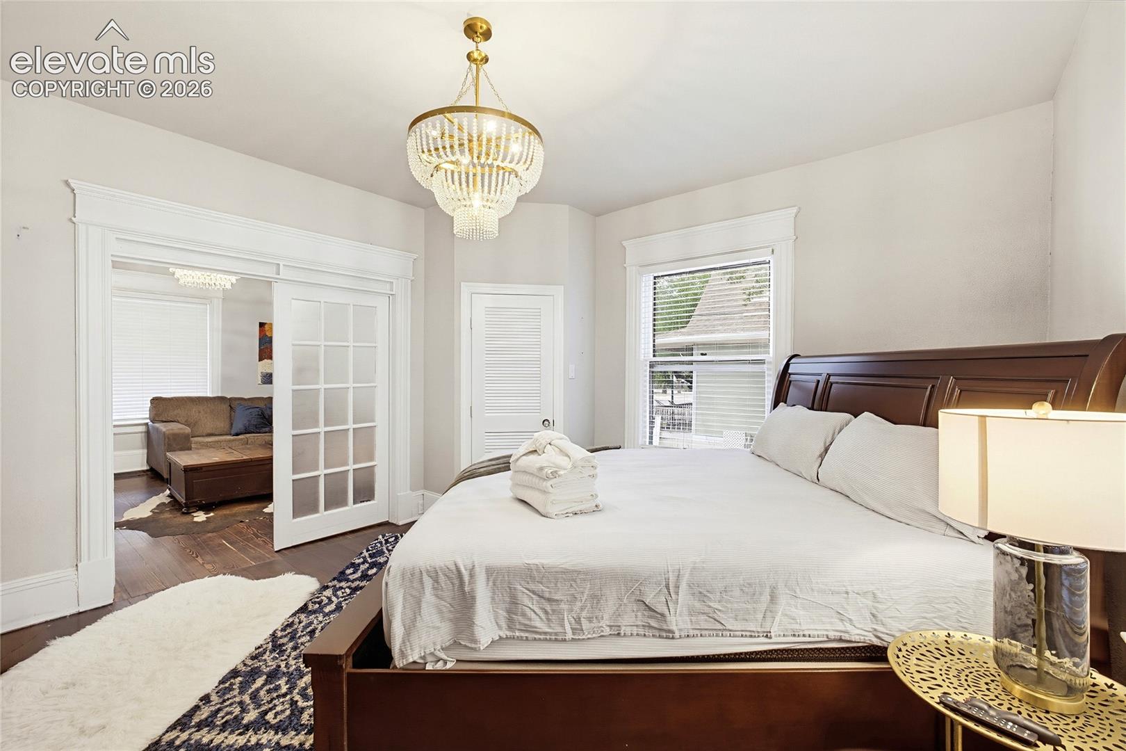 Dark wood-finish flooring, white trim details, window with blinds, and clear paneled sliding doors