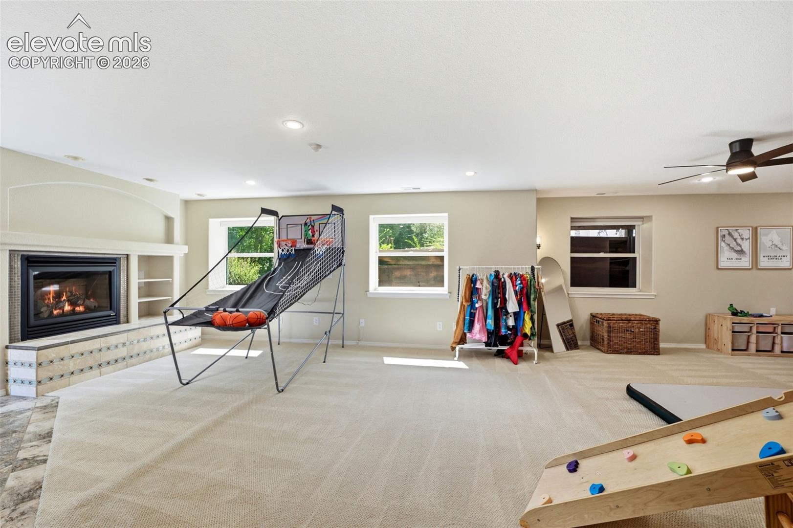 Spacious room featuring a fireplace with a tile hearth, built-in shelving, recessed lighting, and multiple windows