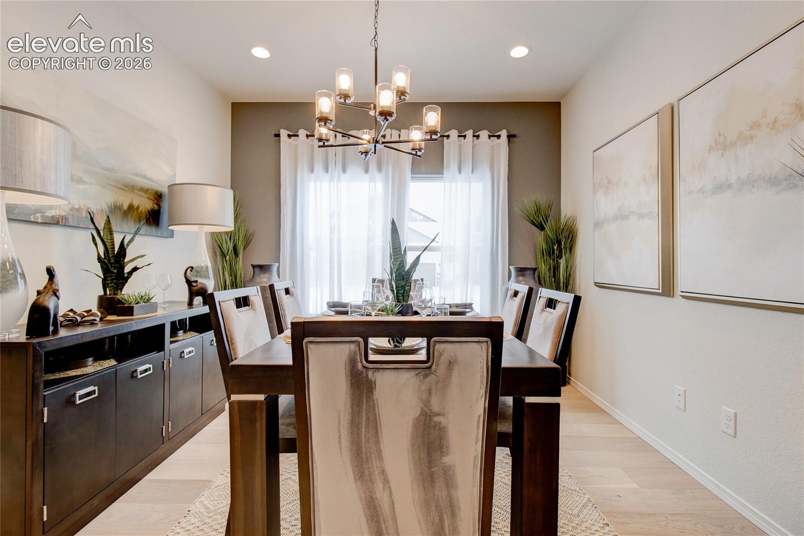 Dining area featuring wood-finish flooring, a contemporary multi-light metal chandelier, and a built-in dark cabinetry unit with rectangular hardware