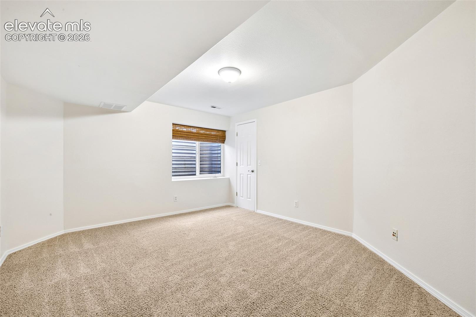 Basement bedroom, Carpeted room with white walls, a single window, recessed lighting, and a white interior door
