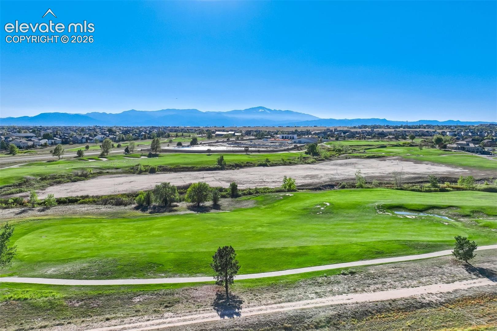 Expansive green space featuring golf course fairways, distant mountain ranges, and scattered trees