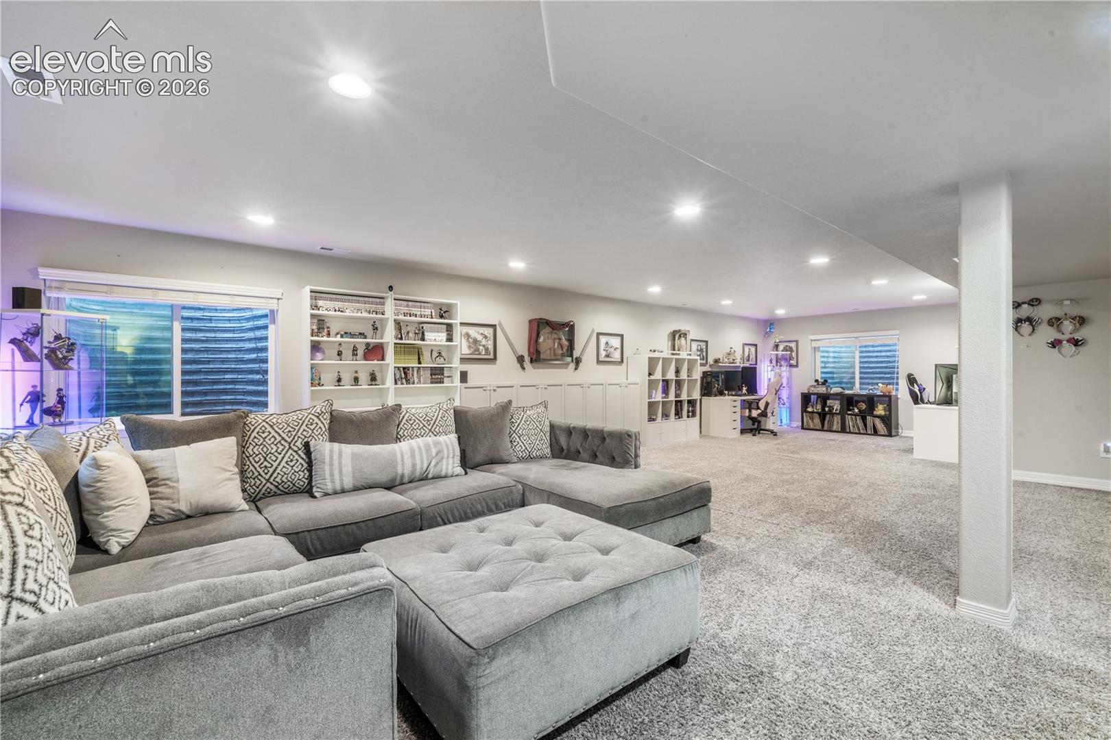 Spacious finished basement with recessed lighting, carpet flooring, built-in shelving, and egress windows