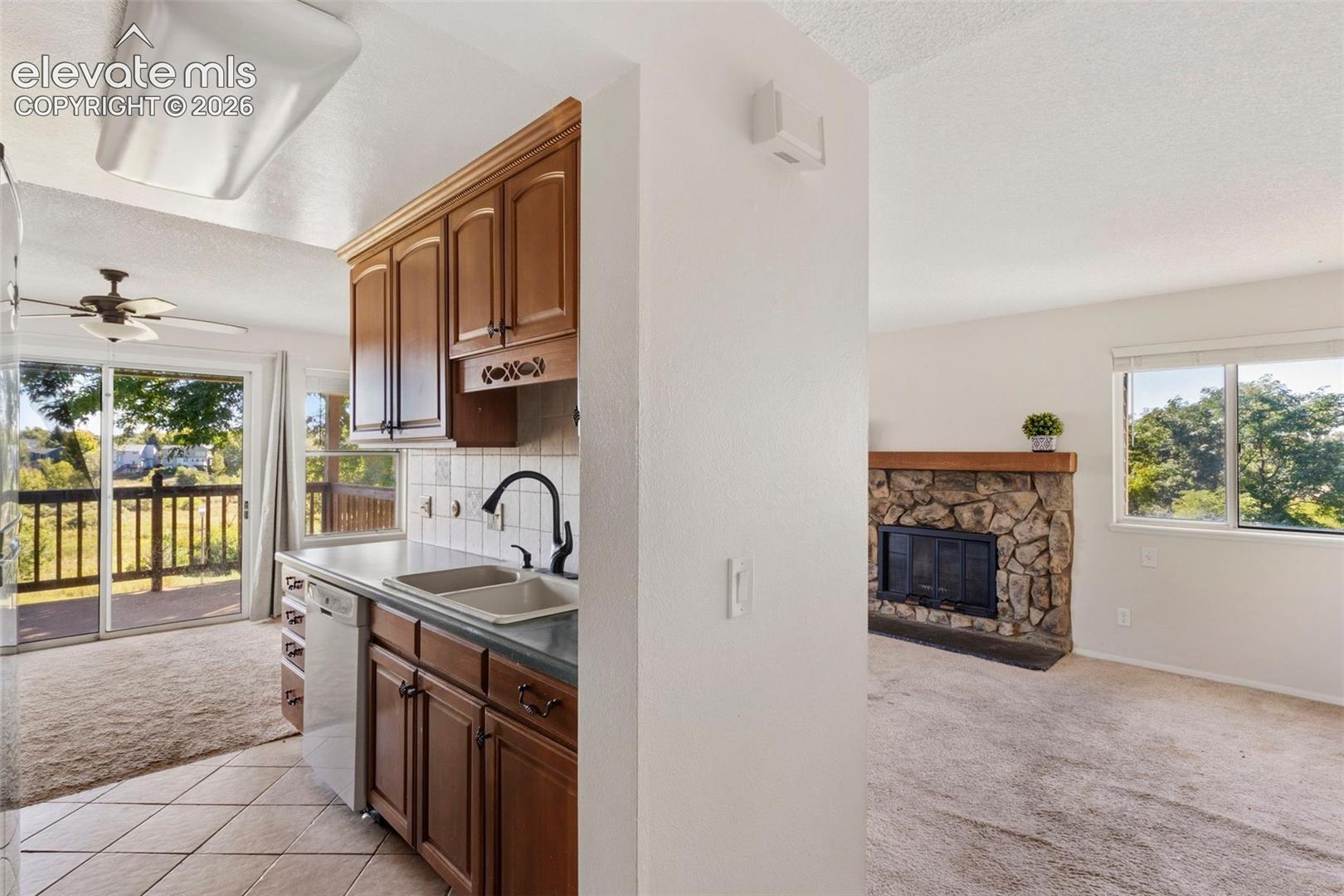 Kitchen with wood cabinetry, dual basin sink, and tile flooring