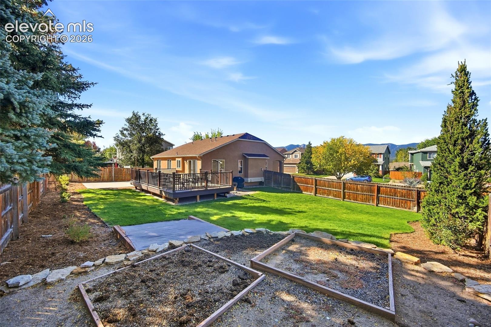 Expansive backyard featuring a manicured lawn, wood-toned privacy fencing, and mature trees