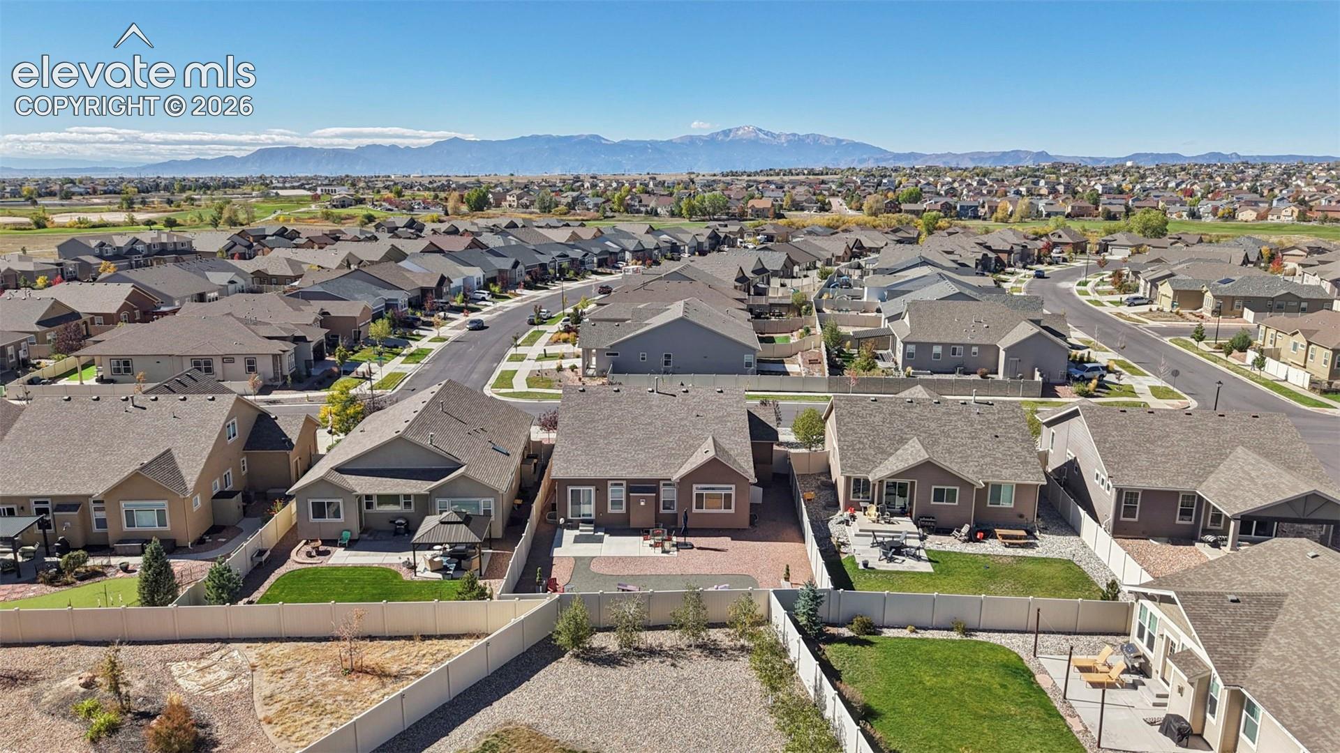 Aerial perspective featuring a paver patio and residential setting with a mountain backdrop