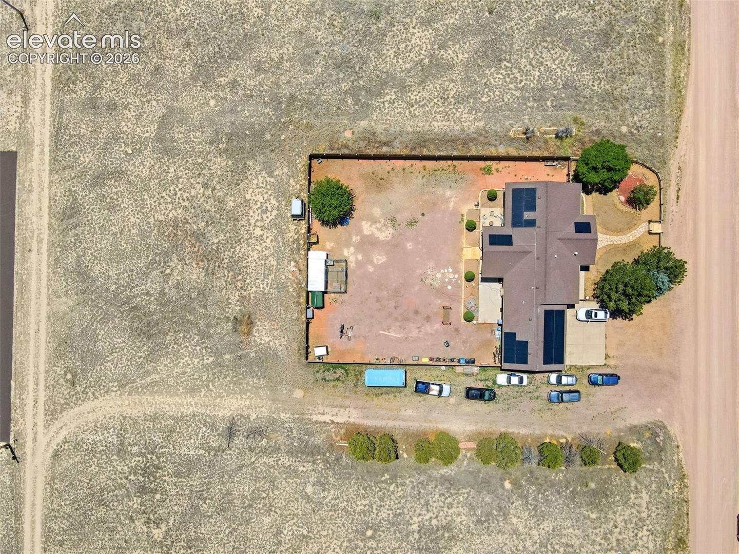 Expansive property featuring a central residence with a brown shingle roof and multiple solar panel installations
