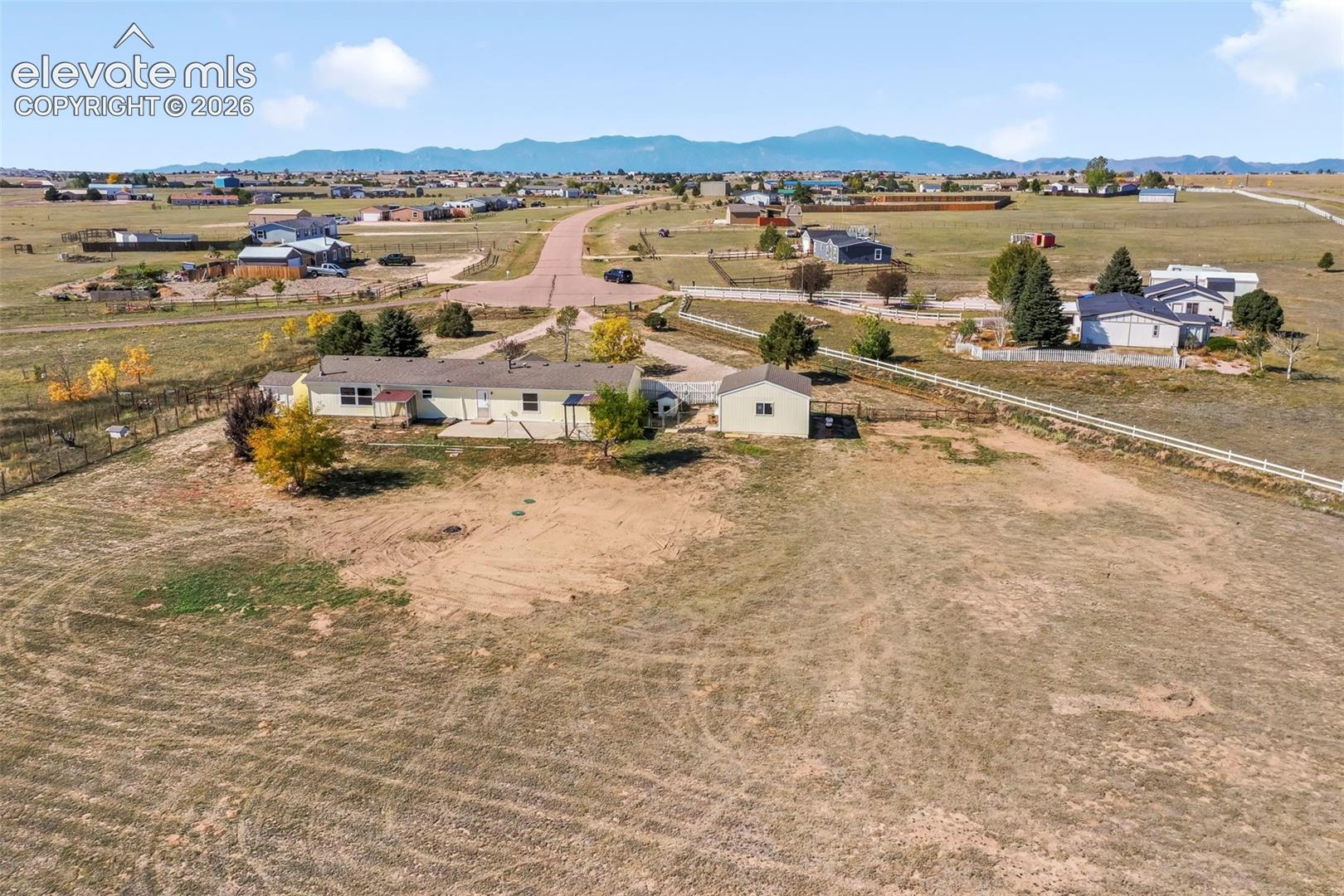 Expansive rural property featuring a single-story residence, detached outbuilding, and distant mountain range