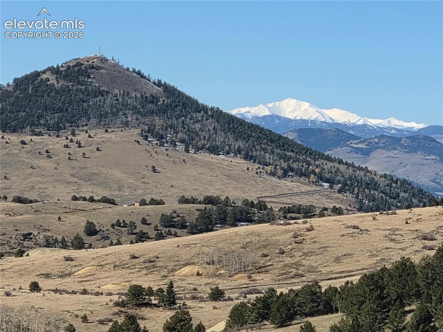 Beautiful surroundings featuring snow-capped mountain peaks, rolling hillsides, and mature evergreen forests
