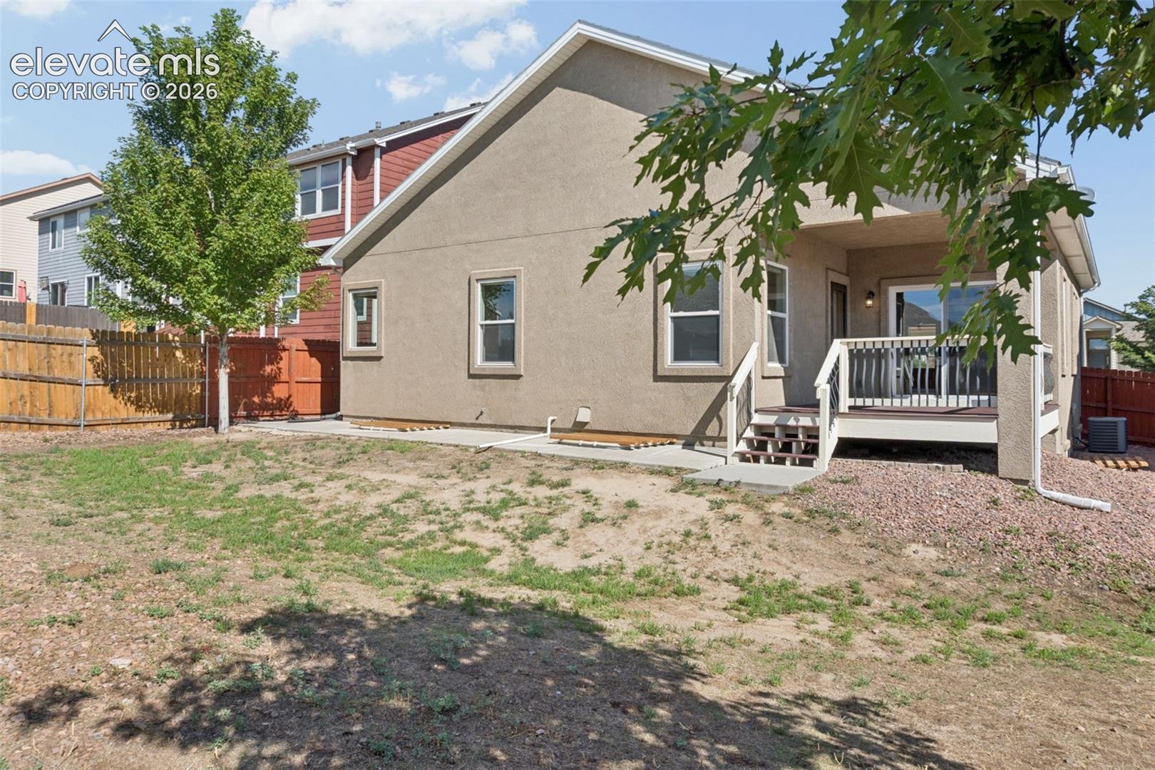 Rear exterior featuring a covered deck, sliding glass door, and stucco siding