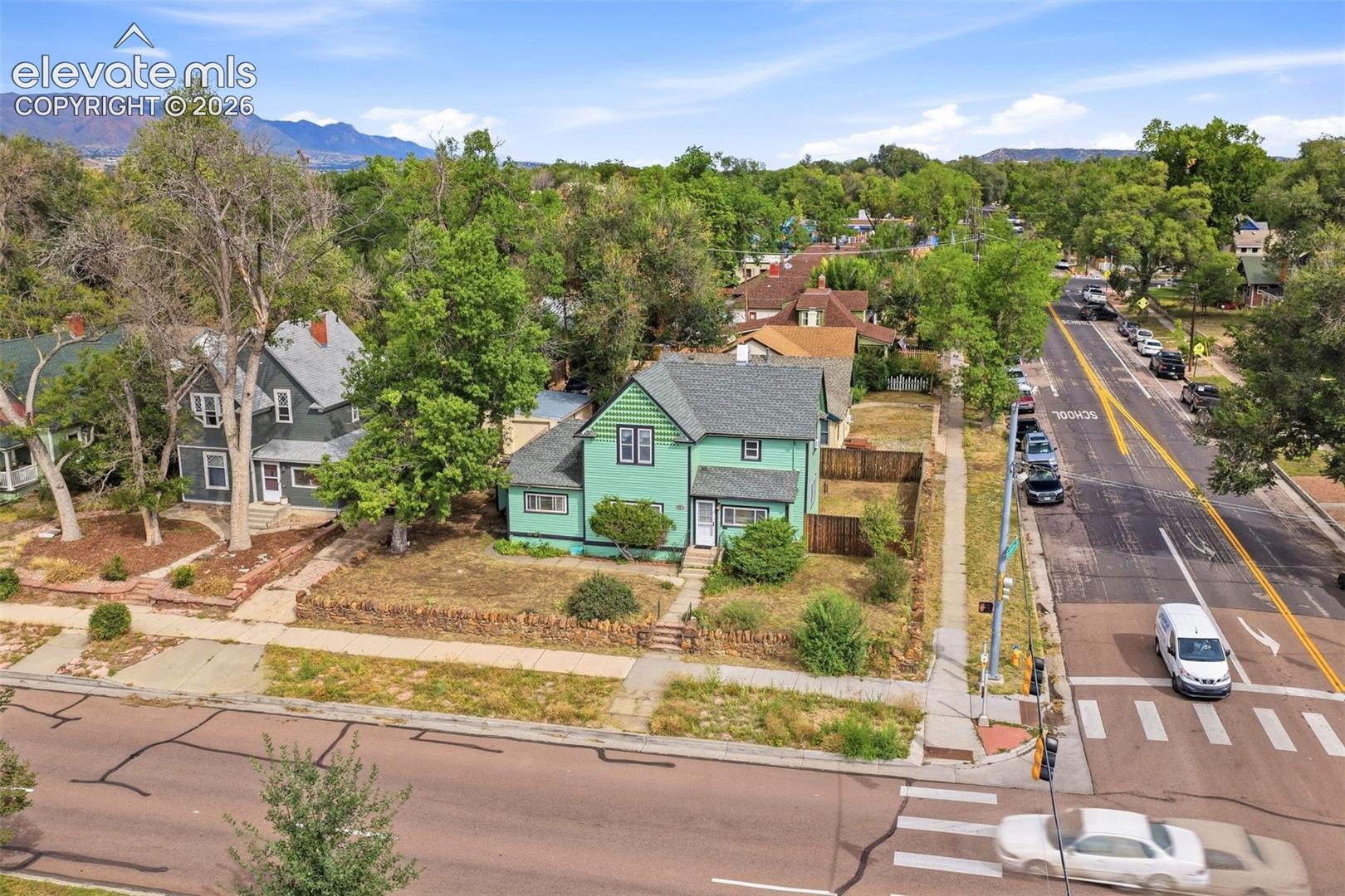 Gable roof design, multi-story exterior, mature trees, mountain backdrop, and established neighborhood setting