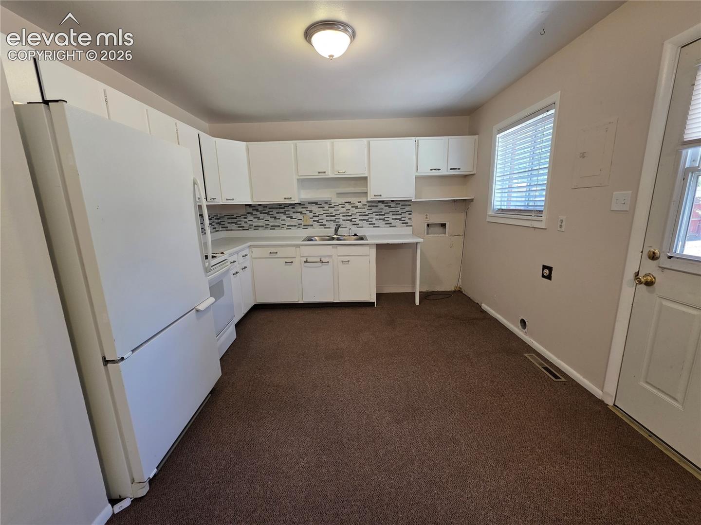 Kitchen featuring white cabinetry, white appliances, a tile backsplash, and a window with blinds