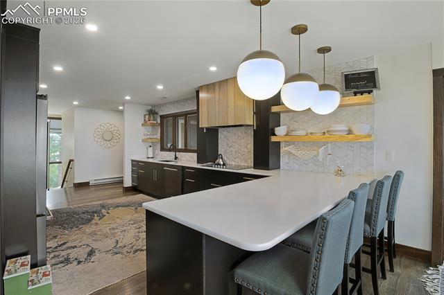 Kitchen featuring open shelves, a peninsula, decorative backsplash, dark wood finished floors, and recessed lighting