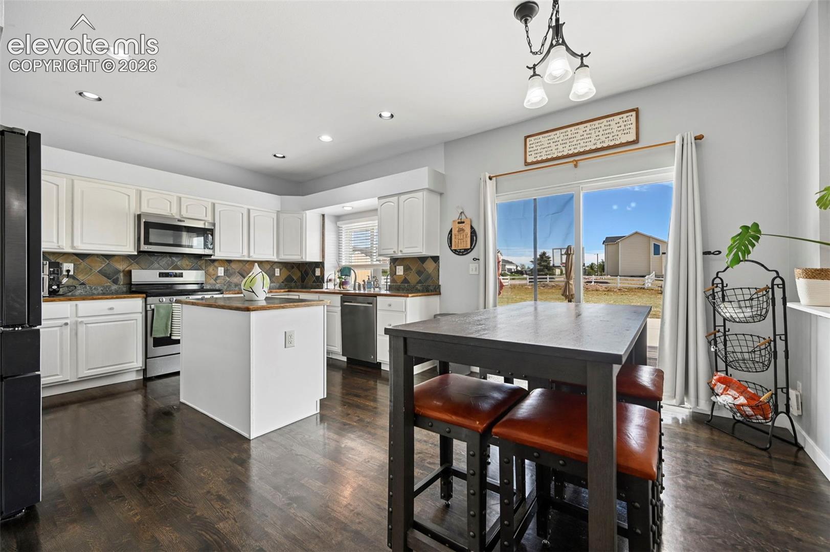Modern kitchen featuring dark wood-finish flooring, white cabinetry, and a central island with wood countertop