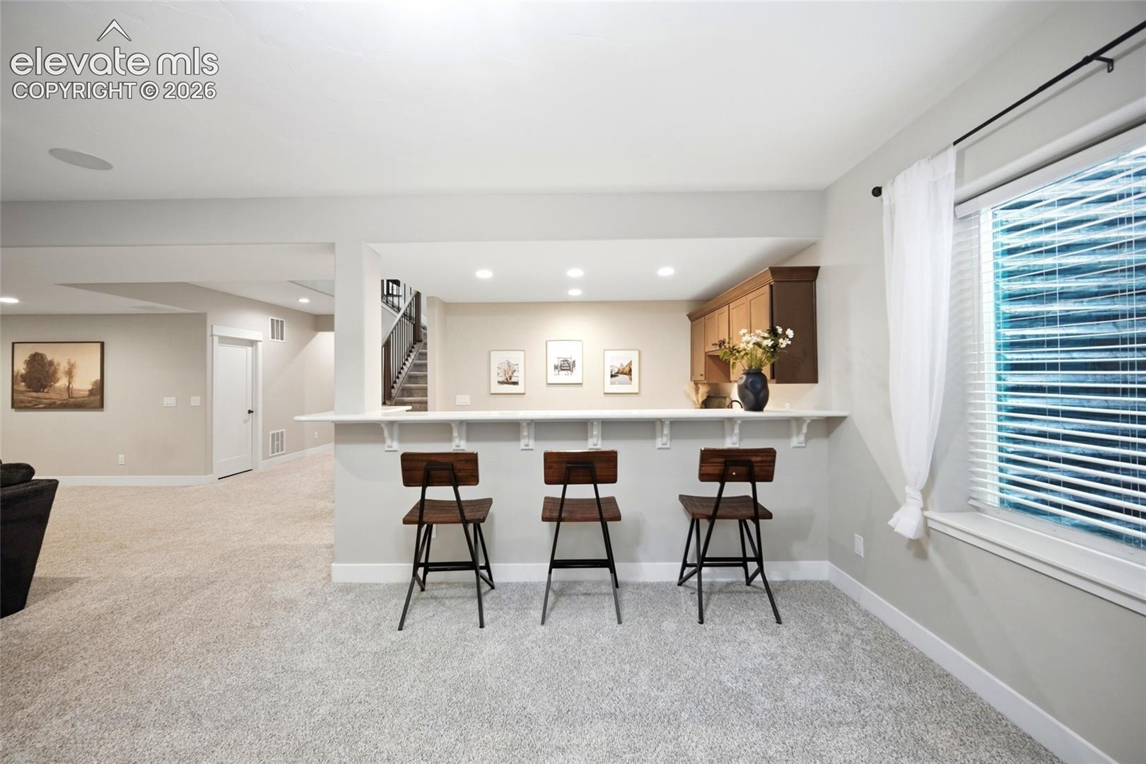 Wet bar featuring built-in wood cabinetry, a pass-through counter with corbel supports, and recessed ceiling lighting