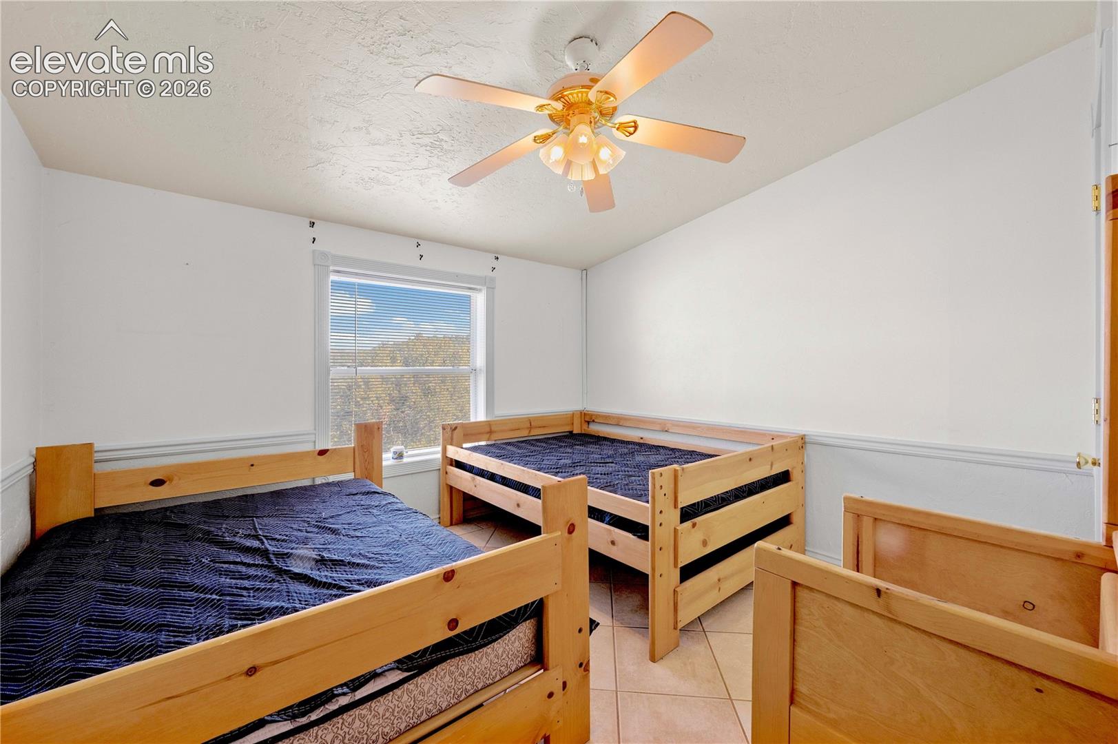 Tiled bedroom with ceiling fan and a textured ceiling