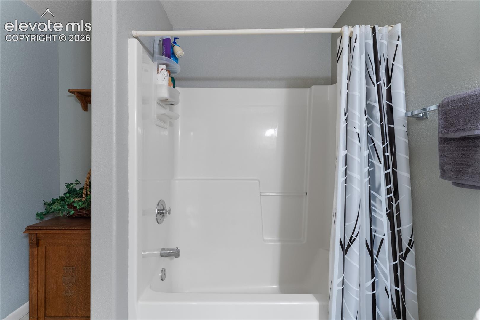 White fiberglass tub and shower combination with chrome fixtures