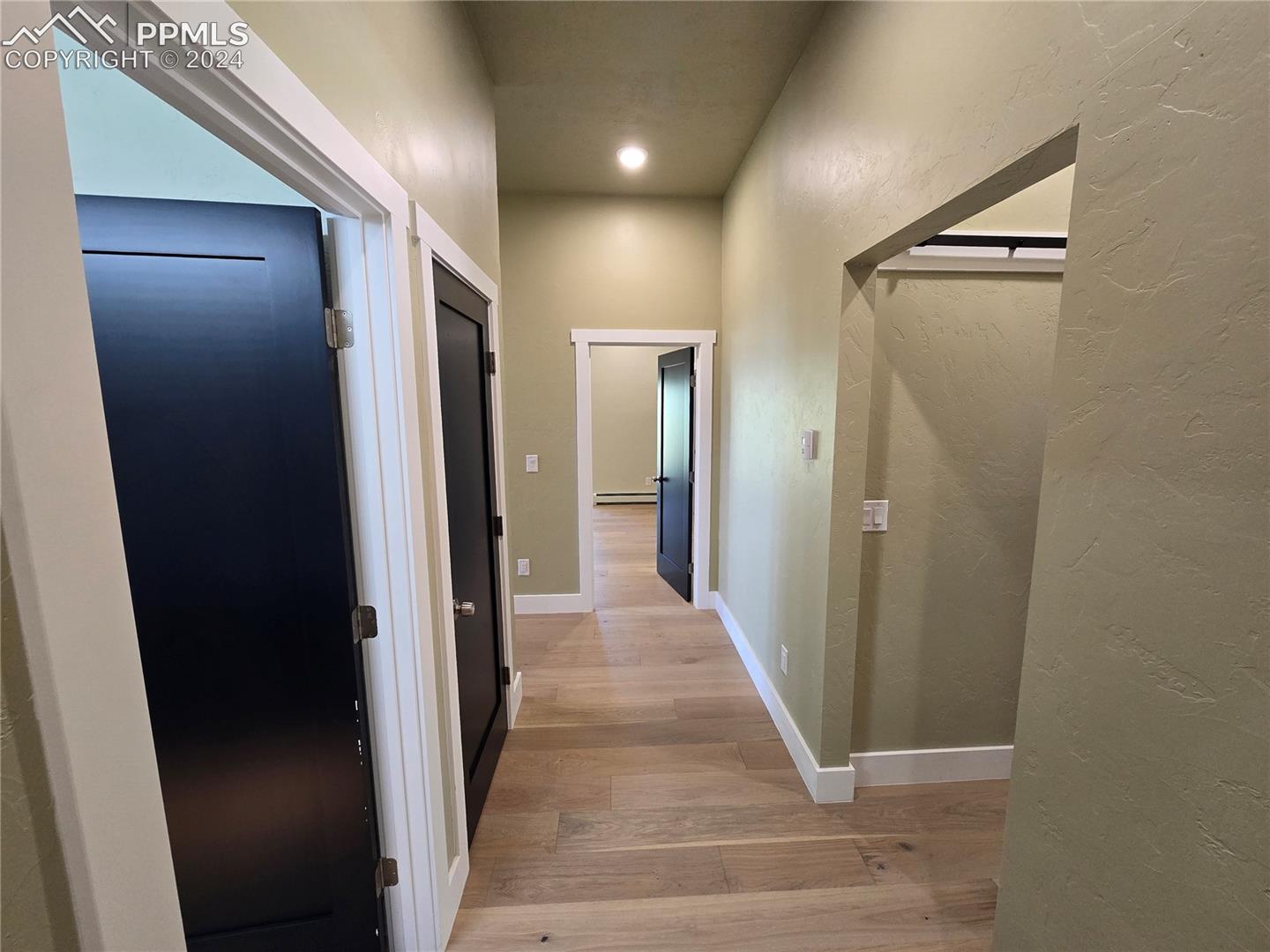 Corridor with light hardwood / wood-style flooring and a baseboard radiator