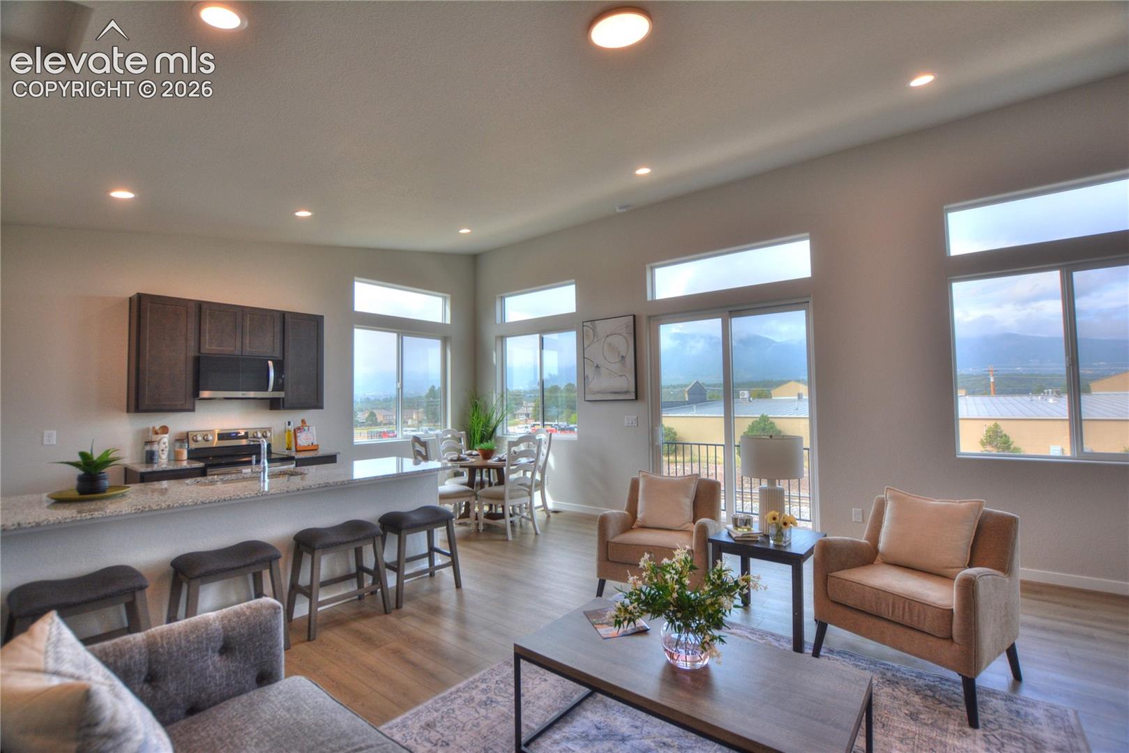 Open-concept living space with wood-finish flooring, recessed lighting, and a kitchen island with seating