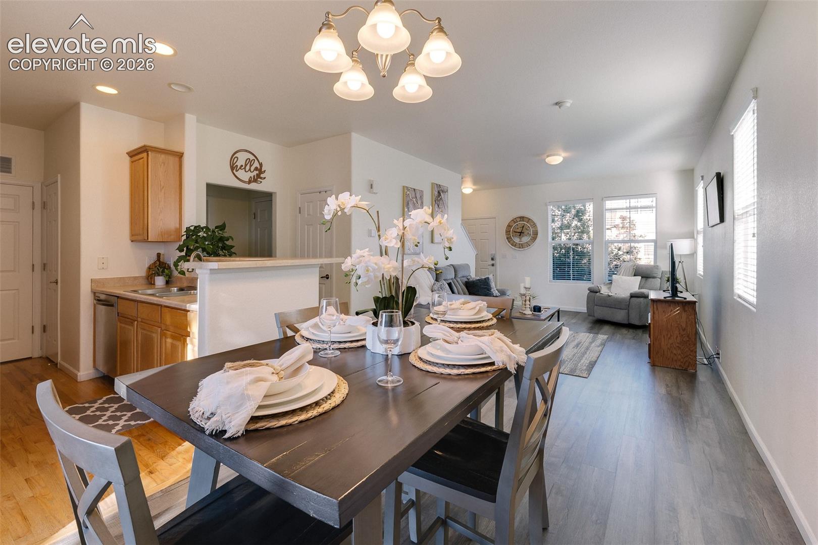 Open-concept living space featuring wood-finish flooring, recessed lighting, a kitchen with wood cabinetry, and a dining area with a chandelier