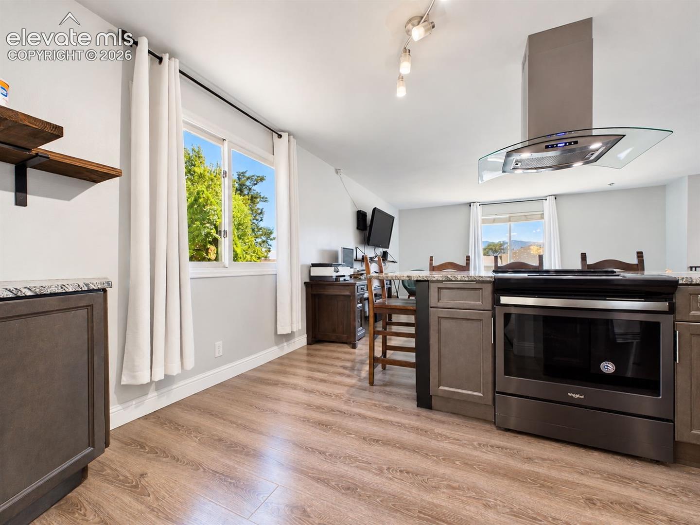 Open kitchen view highlights the island cooking station with contemporary vent hood, updated flooring, and a direct connection to the living area.