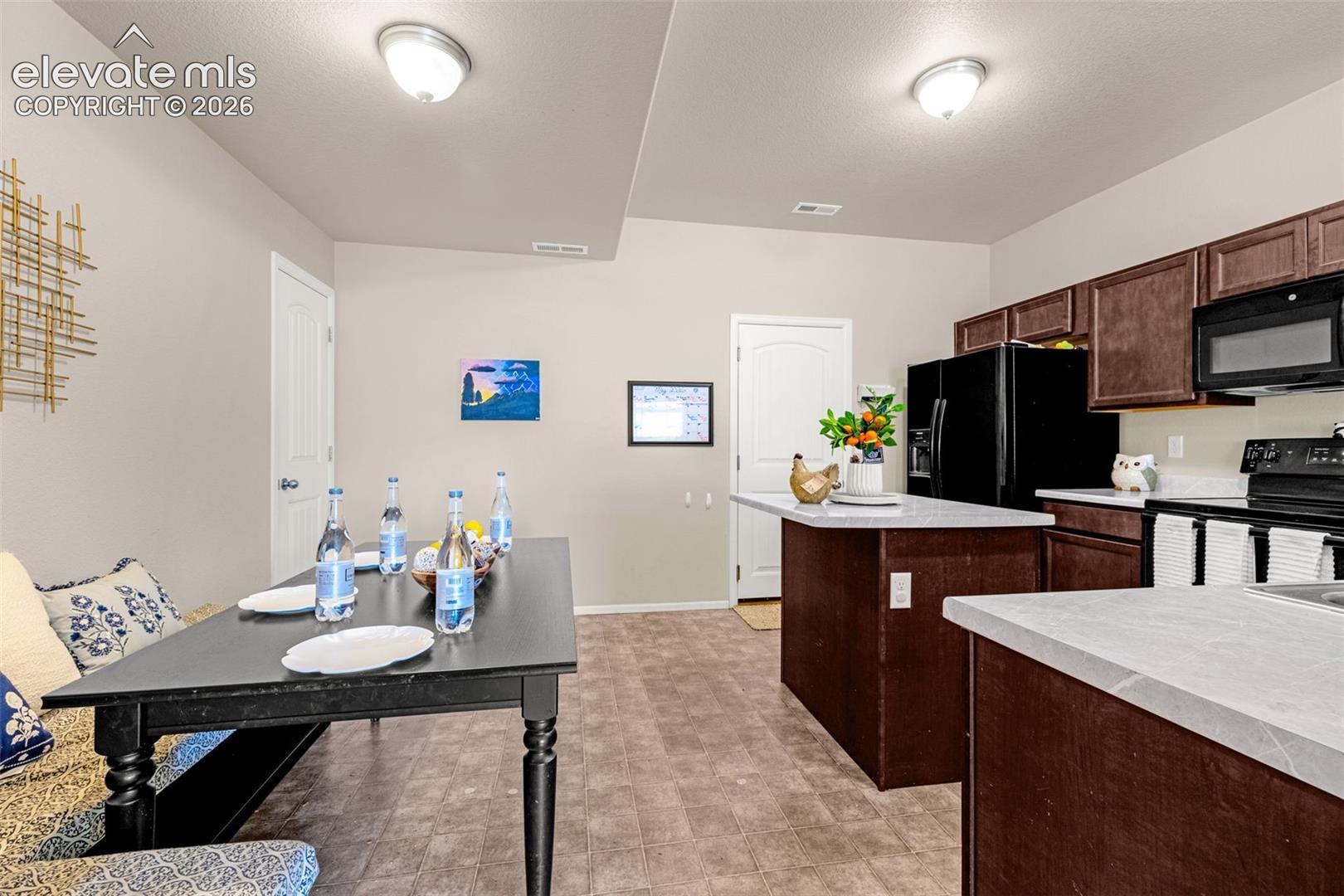 Integrated kitchen and dining area with dark wood-finish cabinetry, light-toned countertops, and durable flooring