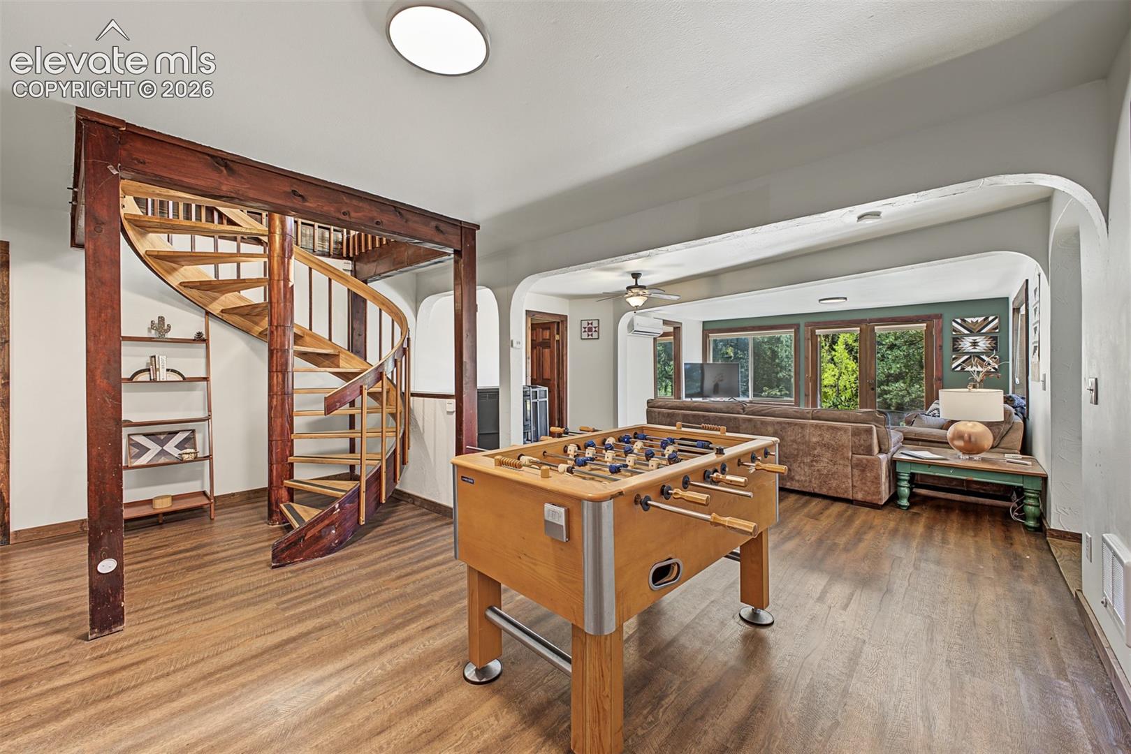 Spiral staircase with wood treads, wood-finish flooring, and recessed lighting