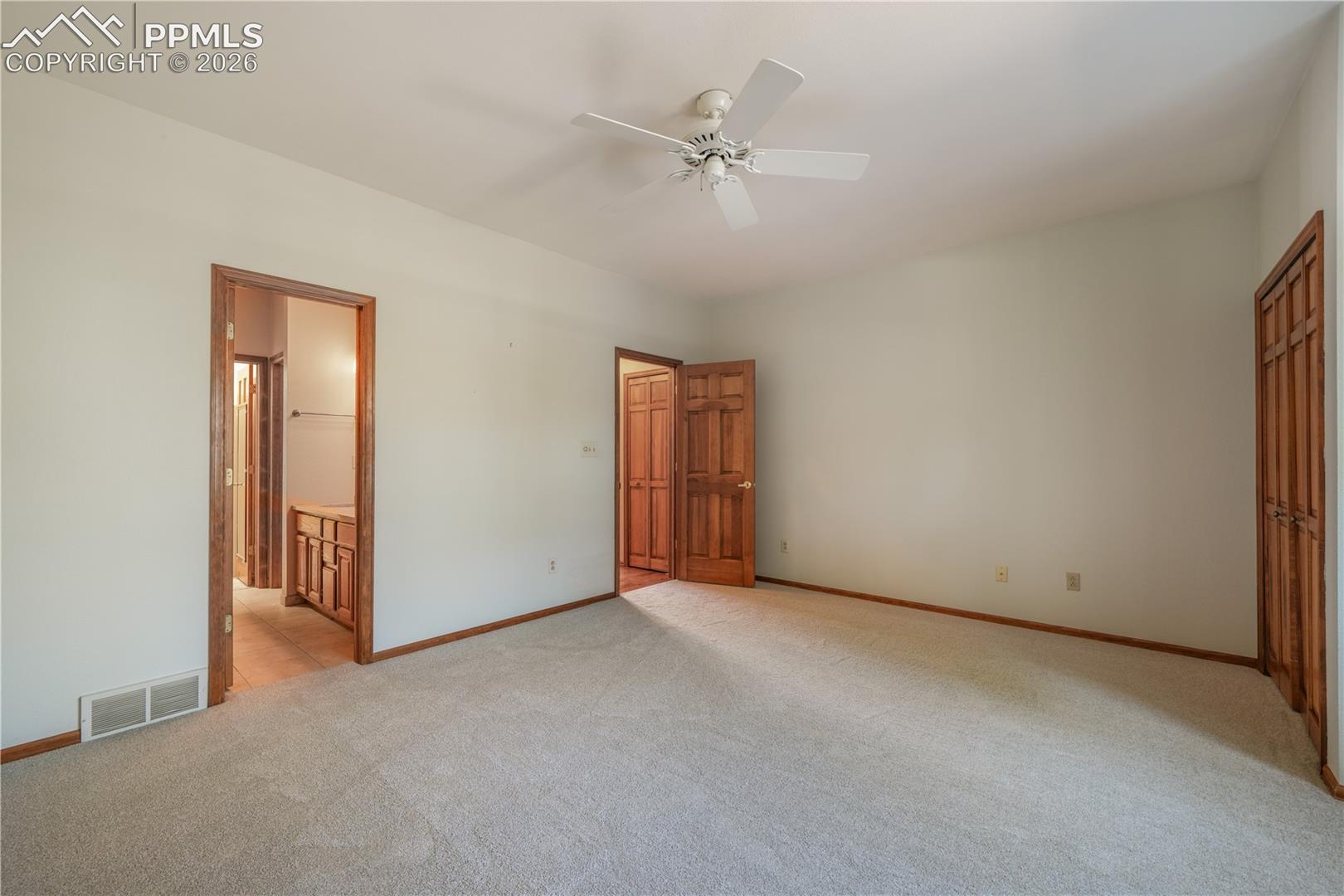 Main level primary bedroom with new carpet, ensuite 5 piece bathroom, walk in closets