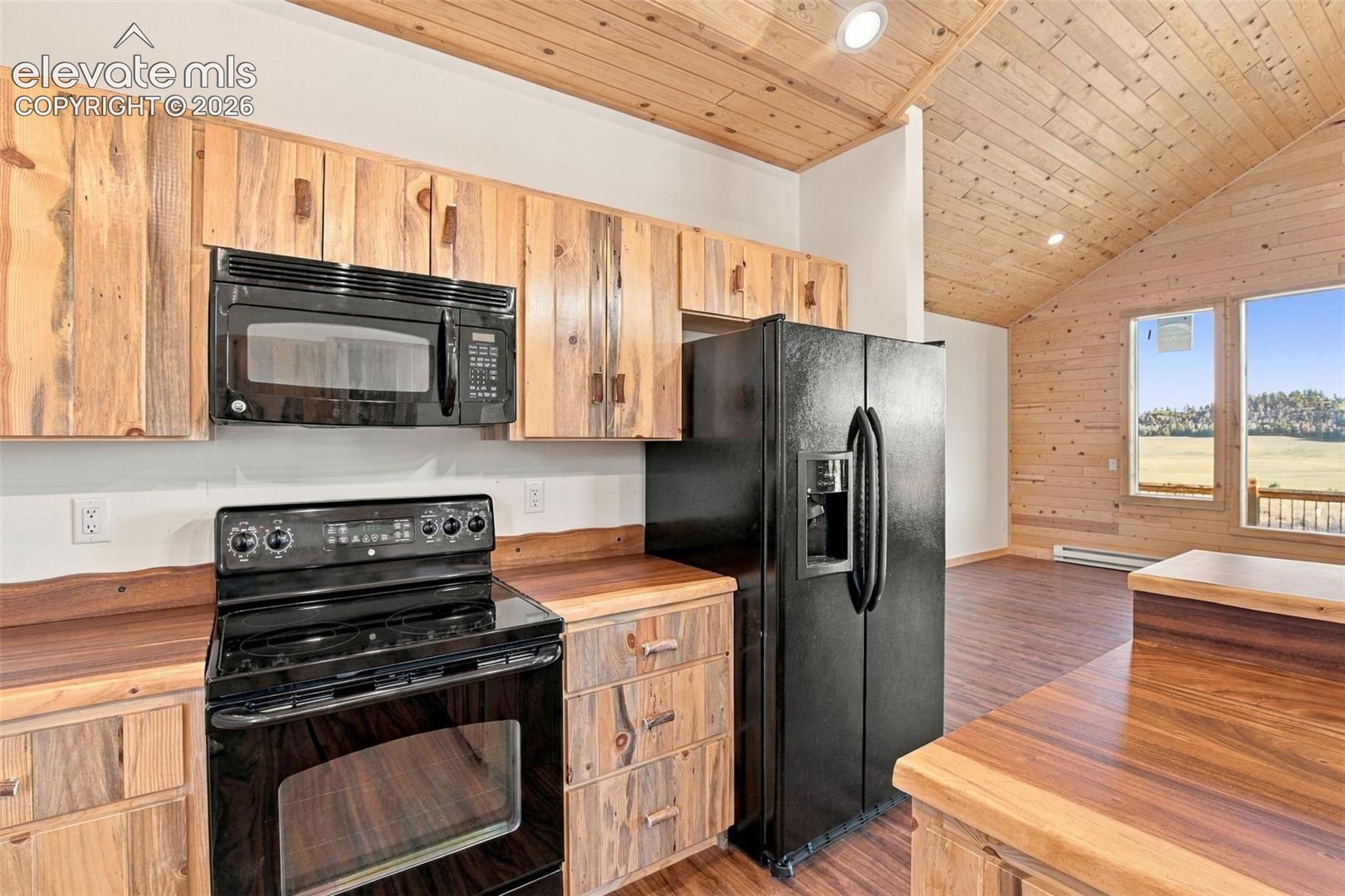 Kitchen featuring rustic wood cabinetry, natural wood-finished plank walls and ceilings, black appliance suite, and custom wood countertops