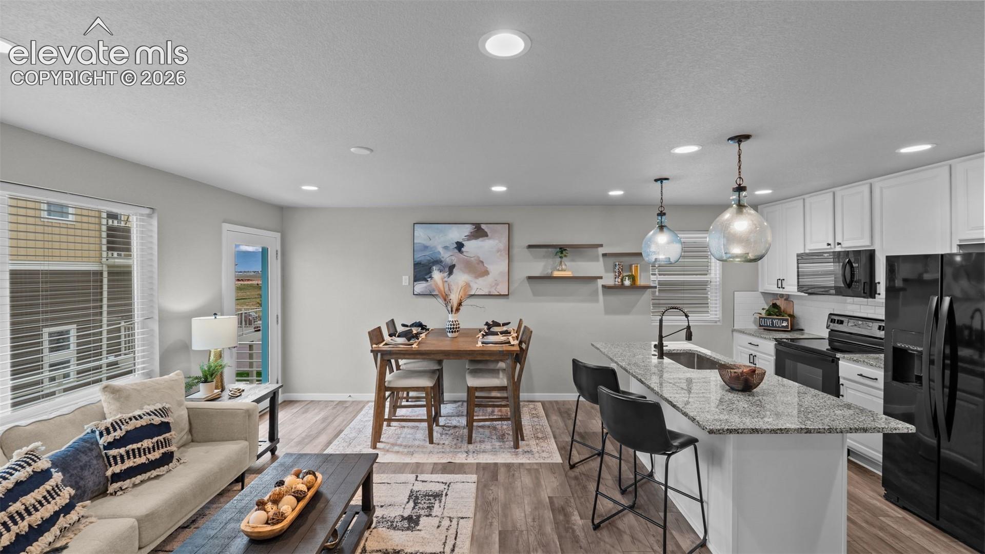Open-concept kitchen featuring an island with stone-finish countertops, white cabinetry, integrated recessed lighting, and wood-finish flooring