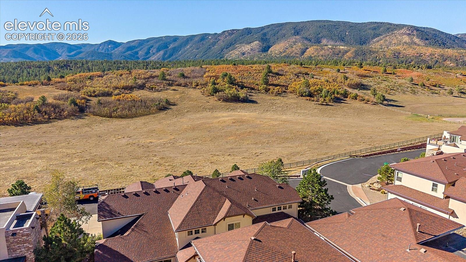 Aerial perspective featuring multi-level structures with composite shingled roofs and expansive open land terrain against a mountain backdrop